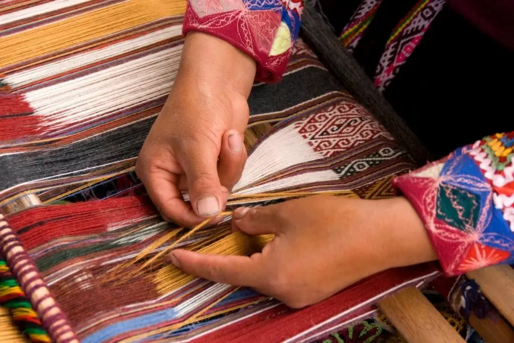 A person weaving colorful alpaca wool