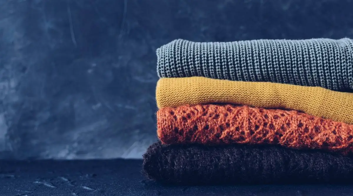 Wool sweaters of different colors with a blue background